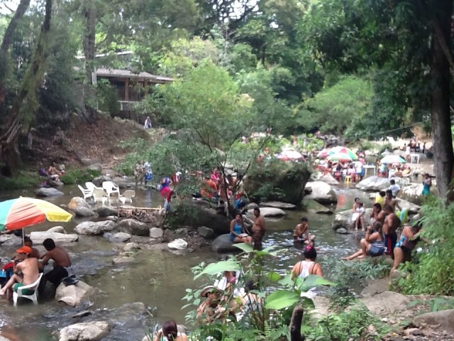 Families having a cook-out while cooling off in the river with their tables, chairs and umbrellas